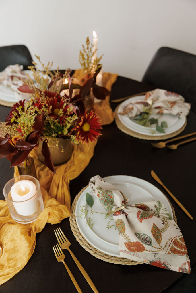Fall-to-holiday tablescape with candles, glassware, and eucalyptus greenery